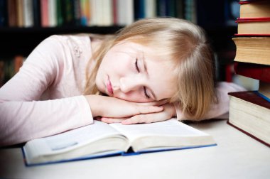 Sevimli küçük kız ödevini yaparken masanın üzerinde yatan.