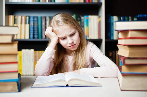 Colère et fatigué écolière étudier avec une pile de livres — Photo
