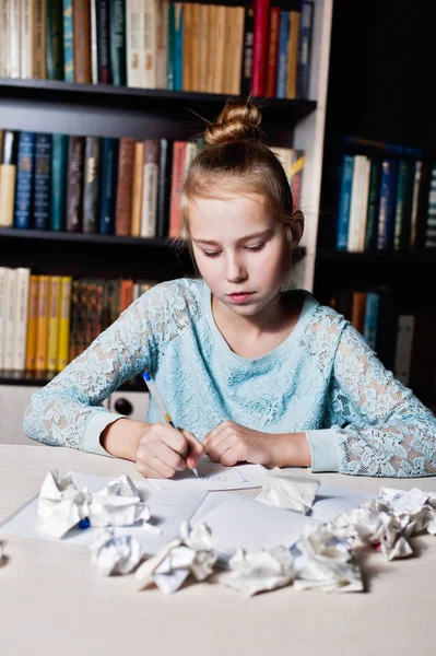 Gadis sekolah duduk di meja dengan pensil di tangan . — Stok Foto