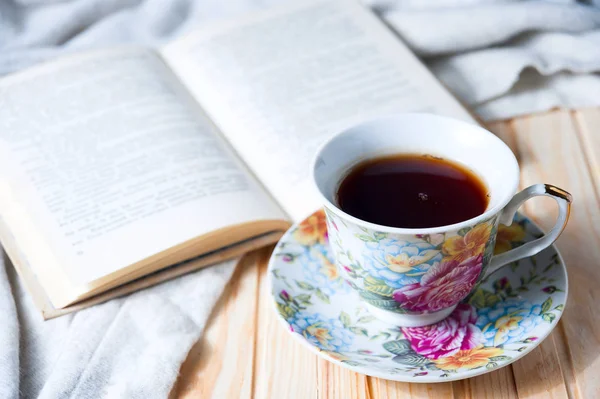 居心地の良いホーム静物: ホット コーヒーまたは紅茶と温かみのあるチェック柄に開いた本のカップ — ストック写真