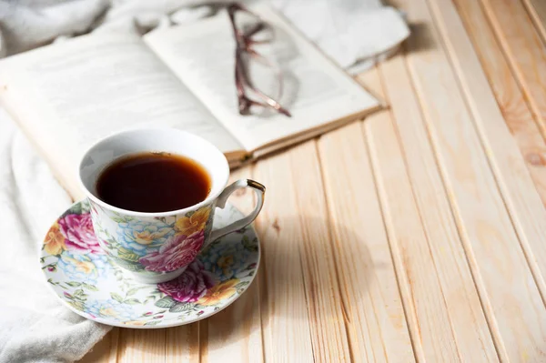 Cup of coffee or tea on wooden table with open book — Stock Photo, Image