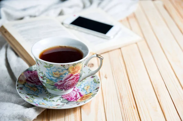 Tea cup placed on a wooden table with a smart phone, glasses, books. Copy space — Stock Photo, Image