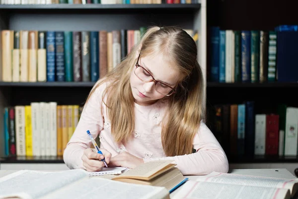 Petite fille intelligente avec des lunettes écrit sur le livre , — Photo