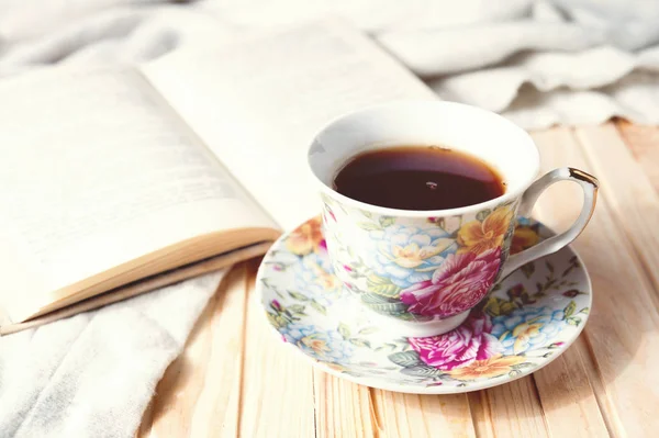 Cozy home still life: cup of hot coffee or tea and opened book with warm plaid — Stock Photo, Image