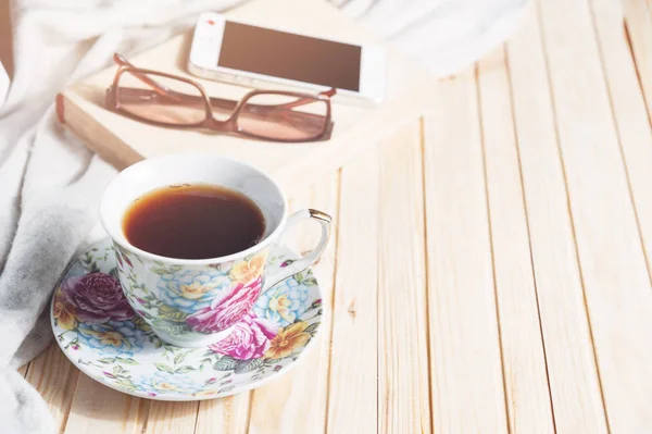 Tea cup placed on a wooden table with a smart phone, glasses, books. Copy space — Stock Photo, Image