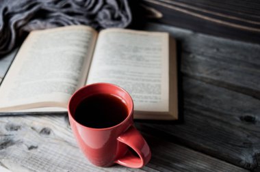gri rahat örme atkı seçici odak fotoğraf ile fincan kahve ya da çay ve ahşap bir masa üzerinde açık kitap.