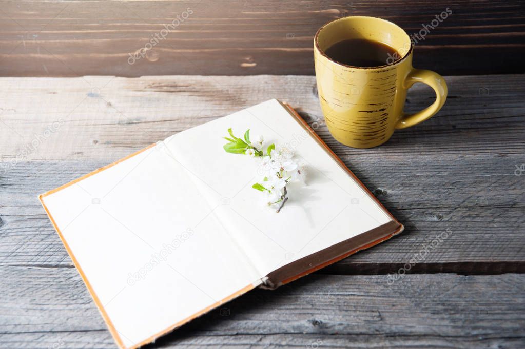 blank book cover on wood background with spring flower and cape of coffee