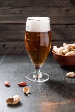 bardak hafif soğuk köpüklü bira, eski bir ahşap zemin üzerine fındık