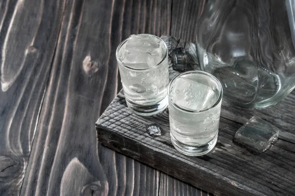 Dois copos de tiro com vodka frio na mesa de madeira, foco seletivo — Fotografia de Stock