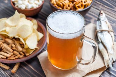 Lager bira bardağı ve ahşap masa snacks. Kuruyemiş, cips, kraker ve kuru balık