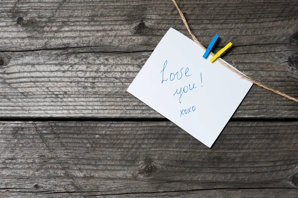 Clothespin, metin, arka plan eski ahşap plakalar üzerinde yer asılı beyaz kağıdın.