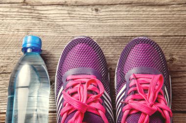 su şişesi ve hafif mor çift koşu ayakkabıları spor ayakkabı koyu ahşap zemin üzerinde. düz üst