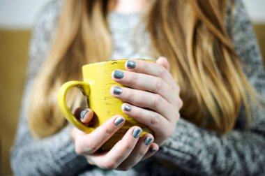 Kız kahve veya çay ile gri gümüş manikür elinde tutuyor