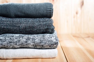 Düzgün bir yığını örme sıcak battaniye ya da kazak gri, Beyaz ahşap arka plan üzerinde.