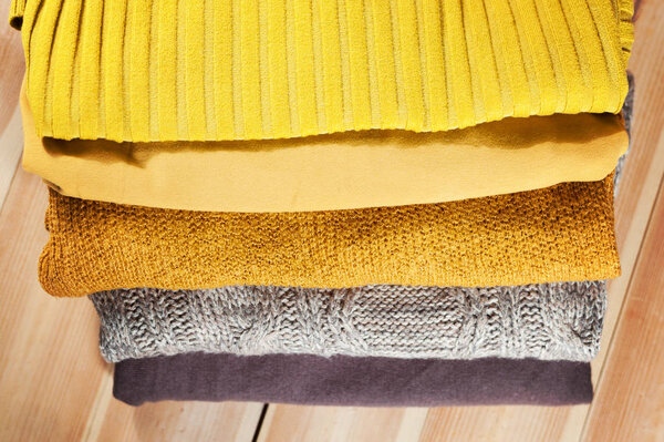 Beautiful photo of a pile of knitted yellow woman sweaters. Woman fashion. Autumn clothing.