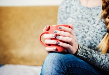 Oturma ve pembe bir fincan çay kahve tutan güzel manikür kadınla