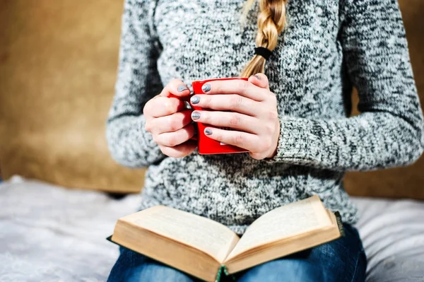 Femme avec une belle manucure tenant une tasse de thé et lisant un livre — Photo