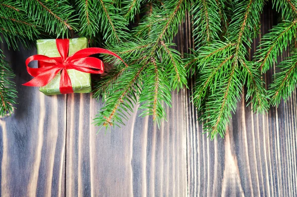 Christmas gift box. Christmas presents with red ribbon at dark wooden table with Christmas tree. Copy space. — Stock Photo, Image