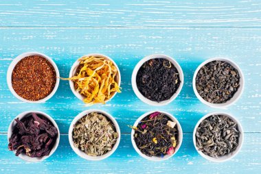 Çeşitli şifalı otlar ve çaylar yukarıdaki mavi ahşap arka plan üzerinde birkaç kase kuru