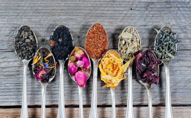 Ahşap zemin üzerine kaşık çay çeşitli. Kuru çay ürün çeşitliliği.