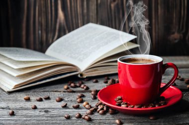 Kırmızı fincan kahve ve kitap günlüğü üzerinde ahşap masa kahve çekirdekleri ile açıldı.