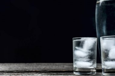 Siyah arka planda shot bardaklarında soğuk votka.