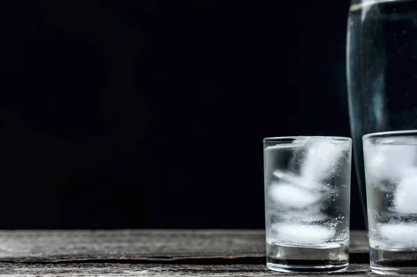 Vodka fria em copos de tiro em um fundo preto — Fotografia de Stock