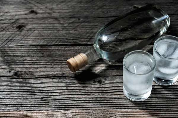 Два рюмки с холодной водкой или джином на деревянном столе , — стоковое фото
