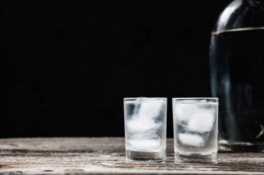 Siyah arka planda shot bardaklarında soğuk votka.