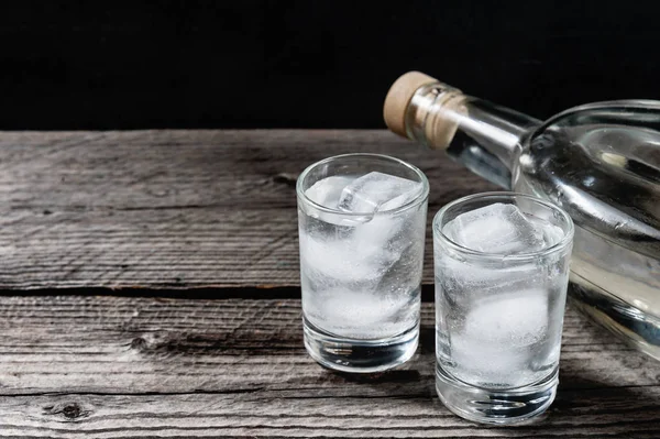 Siyah arka planda shot bardaklarında soğuk votka.