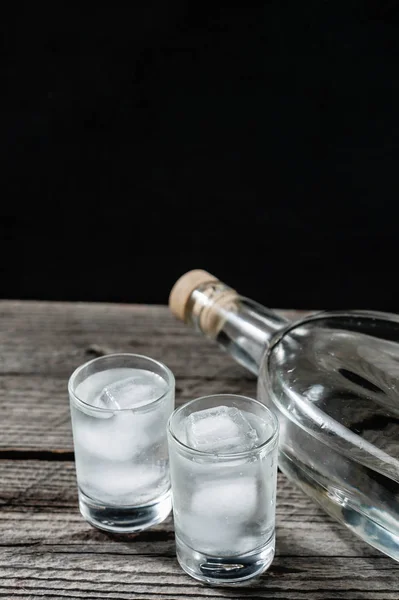 Vodka fria em copos de tiro em um fundo preto — Fotografia de Stock