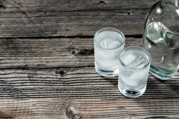 Dois copos de tiro com vodka fria ou gim na mesa de madeira , — Fotografia de Stock