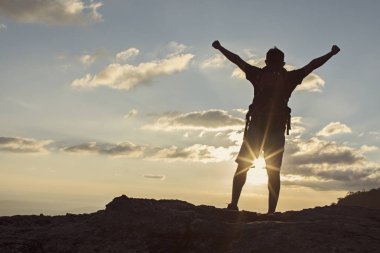 Adam ellerini koyarak, cliff üzerinde duran sırt çantası ile 