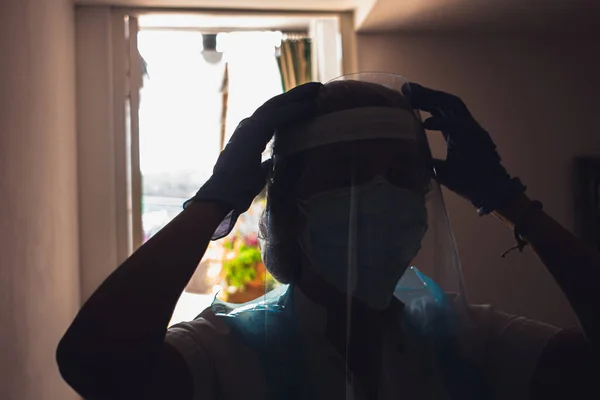 Nurse setting up pandemic equipment to work. The photo is made against the light