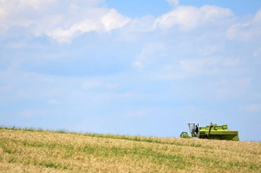 Salzkammergut 'ta (Yukarı Avusturya, Avusturya) bir tahıl tarlasında hasatçı birleştirmek için kış arpasını hasat etmek için bir biçerdöver kullanılır.. -