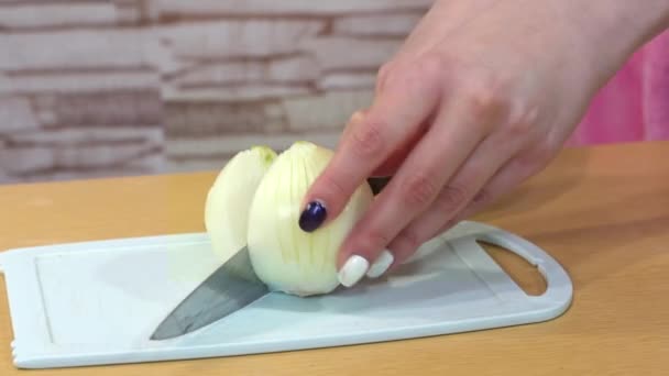 Flicka hand med en fin manikyr skär en lök med en stor kniv — Stockvideo
