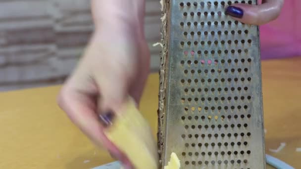 Honhand med manikyr gnuggar ost på rivjärn närbild — Stockvideo