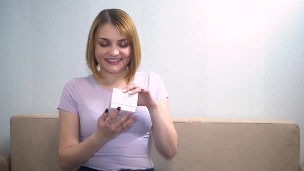 La chica abre la caja y es feliz, sonriente, está emocionada — Vídeos de Stock