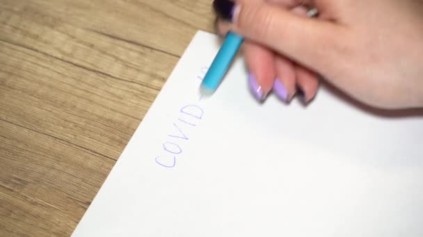 El primer plano de la mano de la mujer borra la escritura en el papel covid - 19 — Vídeos de Stock