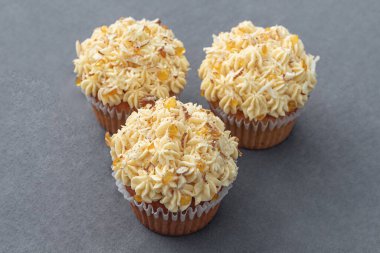 Sarı malzemeli kek, karamel ve fındık, gri arka planda.