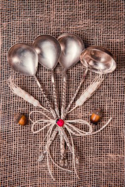 Hassas sicim, buğday, meşe palamudu ve uğur böceği ile süslenmiş bir çuval bezinin üzerinde duran ahşap bir masa üzerindeki çatal bıçak seti (kaşıklar ve kepçe)