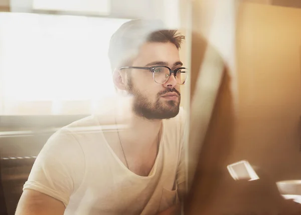 Gelukkig jonge man, bril, als hij op zijn laptop tot en met g werkt — Stockfoto