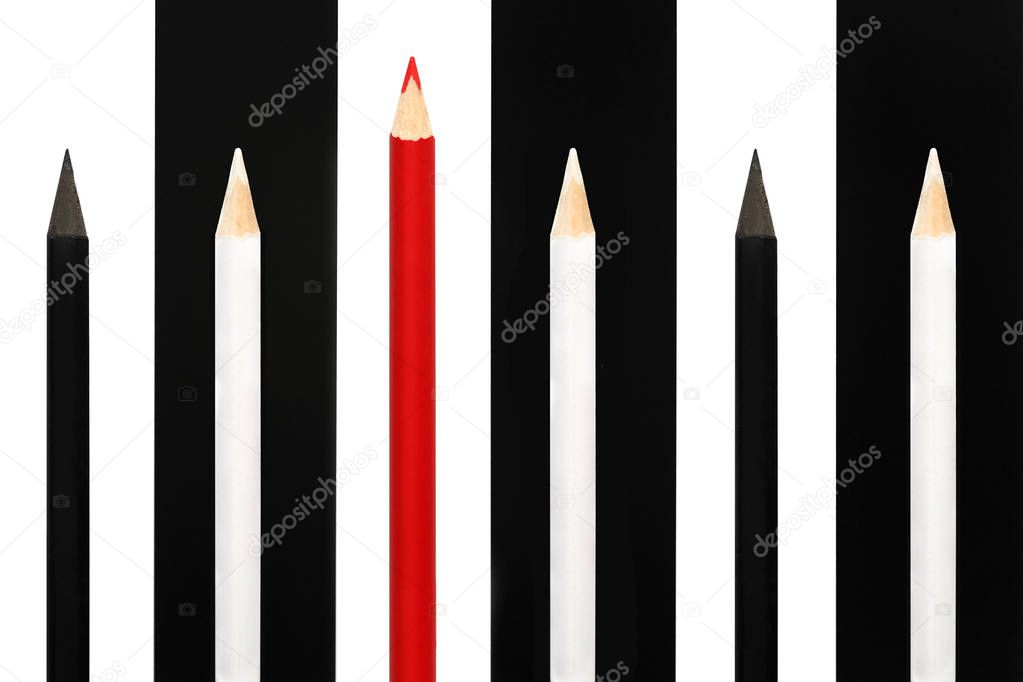 Red pencil standing out from crowd of black and white fellows on bw stripe background. business success concept of leadership uniqueness, independence, initiative, strategy, dissent, think different