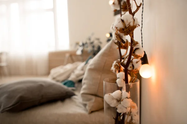 Spring artificial sakura branch with yellow light bulbs in white loft interior in scandinavian style — Stock Photo, Image