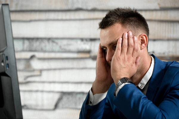 Уставший бизнесмен на рабочем месте в офисе держит голову на ха
