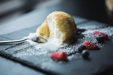 Kızarmış dondurma sosu ve meyve çay kaşığı ile siyah taş plaka ile Hindistan cevizi içinde. Asya gıda arka plan. Beslenme kavramı. Ahşap masa ile Restaraunt yer. Kopya alanı için metin, tasarım