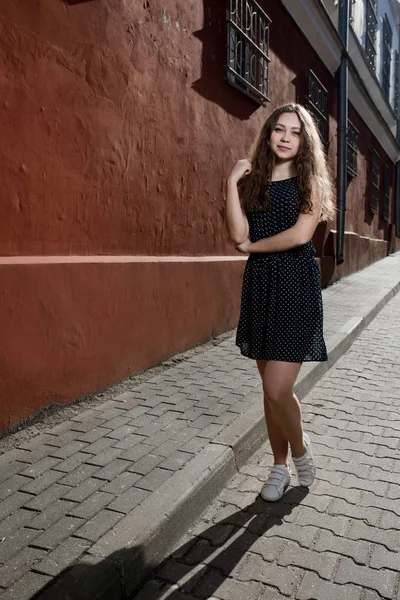 Linda morena jovem vestindo vestido e andando na rua. Flare para texto e design. Estilo de vida na cidade . — Fotografia de Stock