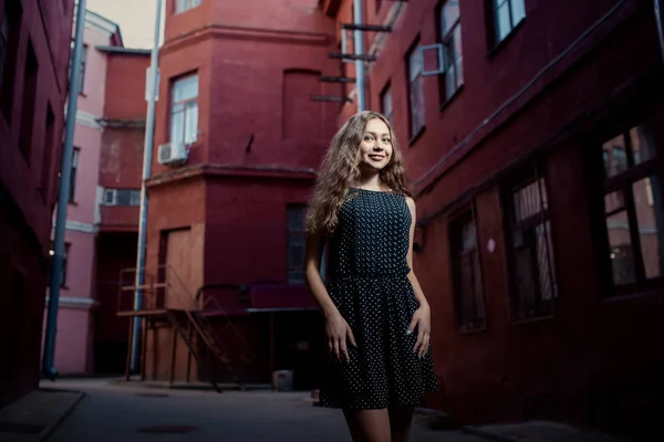 Hermosa joven morena vistiendo vestido y caminando por la calle. Bengalas para texto y diseño. Estilo de vida en la ciudad . — Foto de Stock