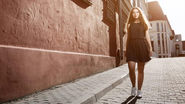 Beautiful brunette young woman wearing dress and walking on the street. Flare for text and design. Lifestyle in the city. — Stock Photo, Image