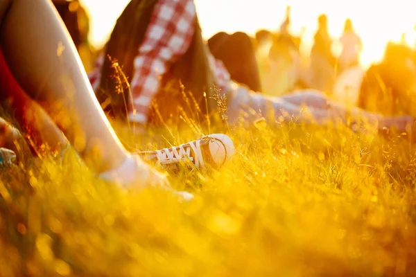 spor ayakkabı ya da spor ayakkabı içinde çim bacaklarda. yaz yaşam tarzı. Renkli sıcak sarı tonlama. İnsanlar tatile yerde yatan. rekreasyon Parkı doğa içinde. Müzik Festivali açık tarih. Nesne fotoğraf.